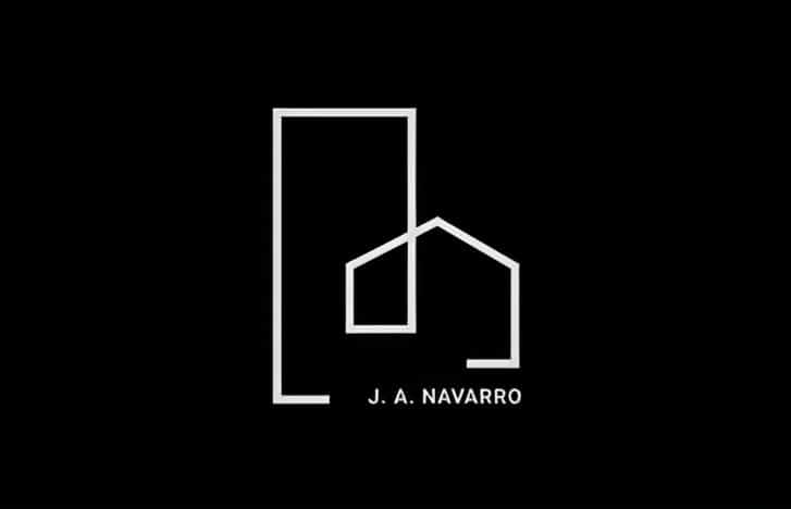 Logotipo minimalista con contornos blancos de un rectángulo alto y la forma de una casa, con el texto "J. A. NAVARRO" debajo, sobre fondo negro.